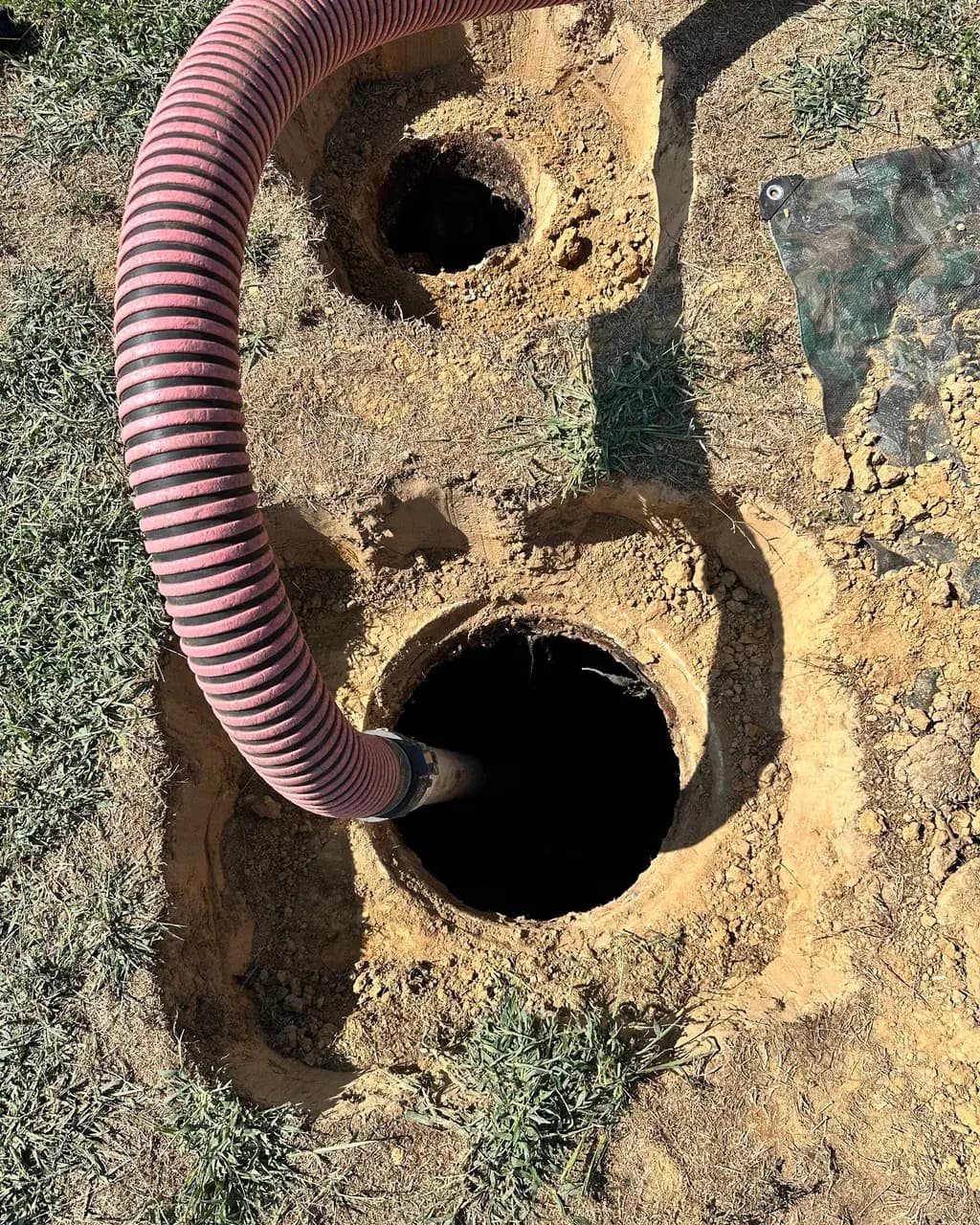 Pump hose running into an open septic tank lid during a Wurth Brothers pump-out